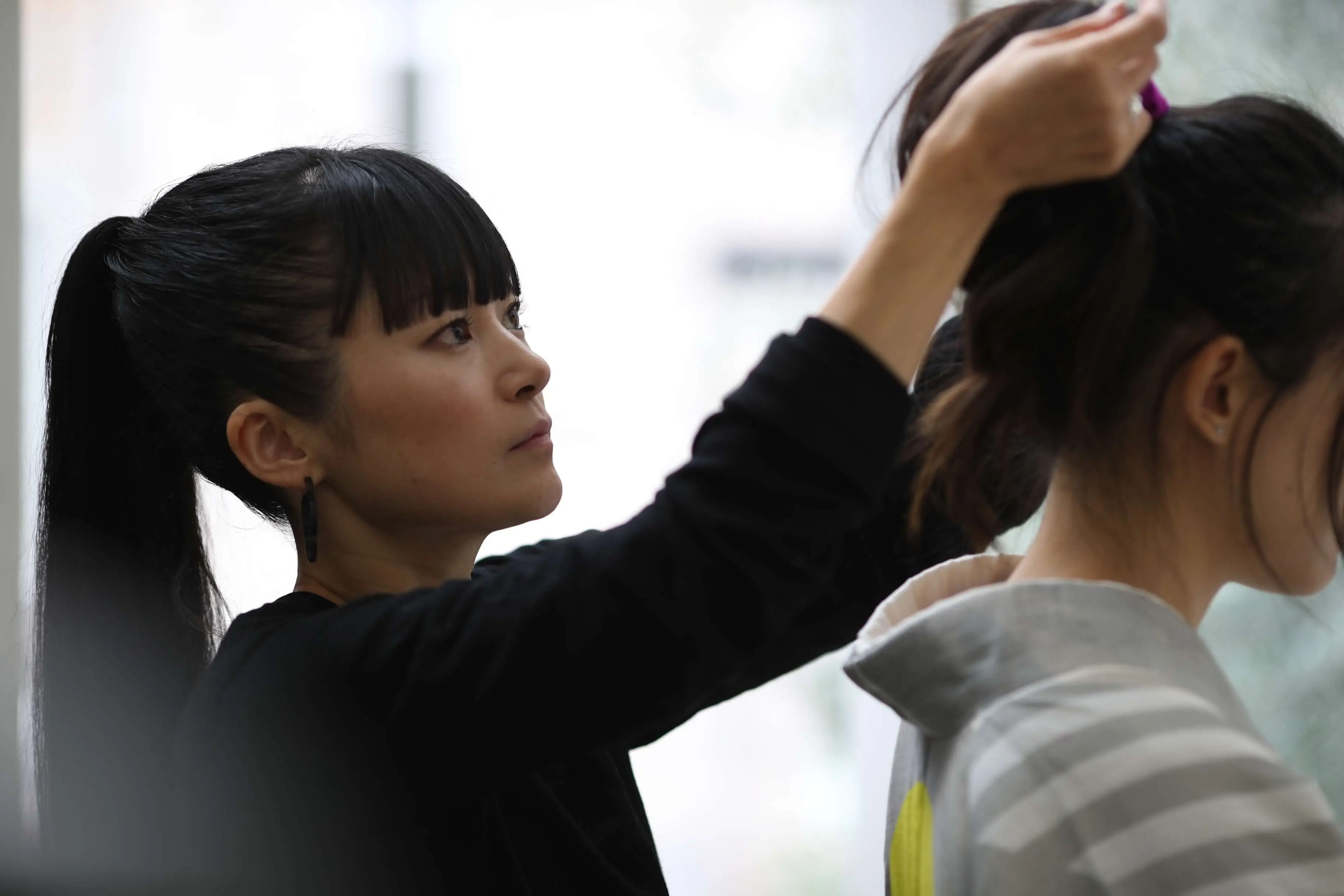 Hiroko Takahashi holds woman’s hair up during kimono fitting.